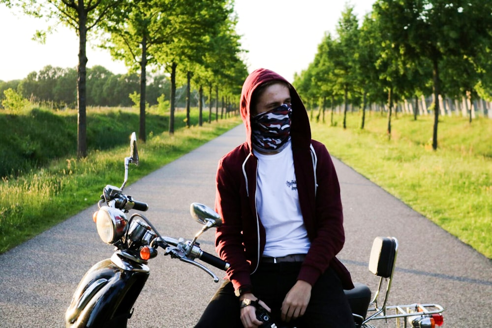 man covering his face with bandanna sitting on motorcycle