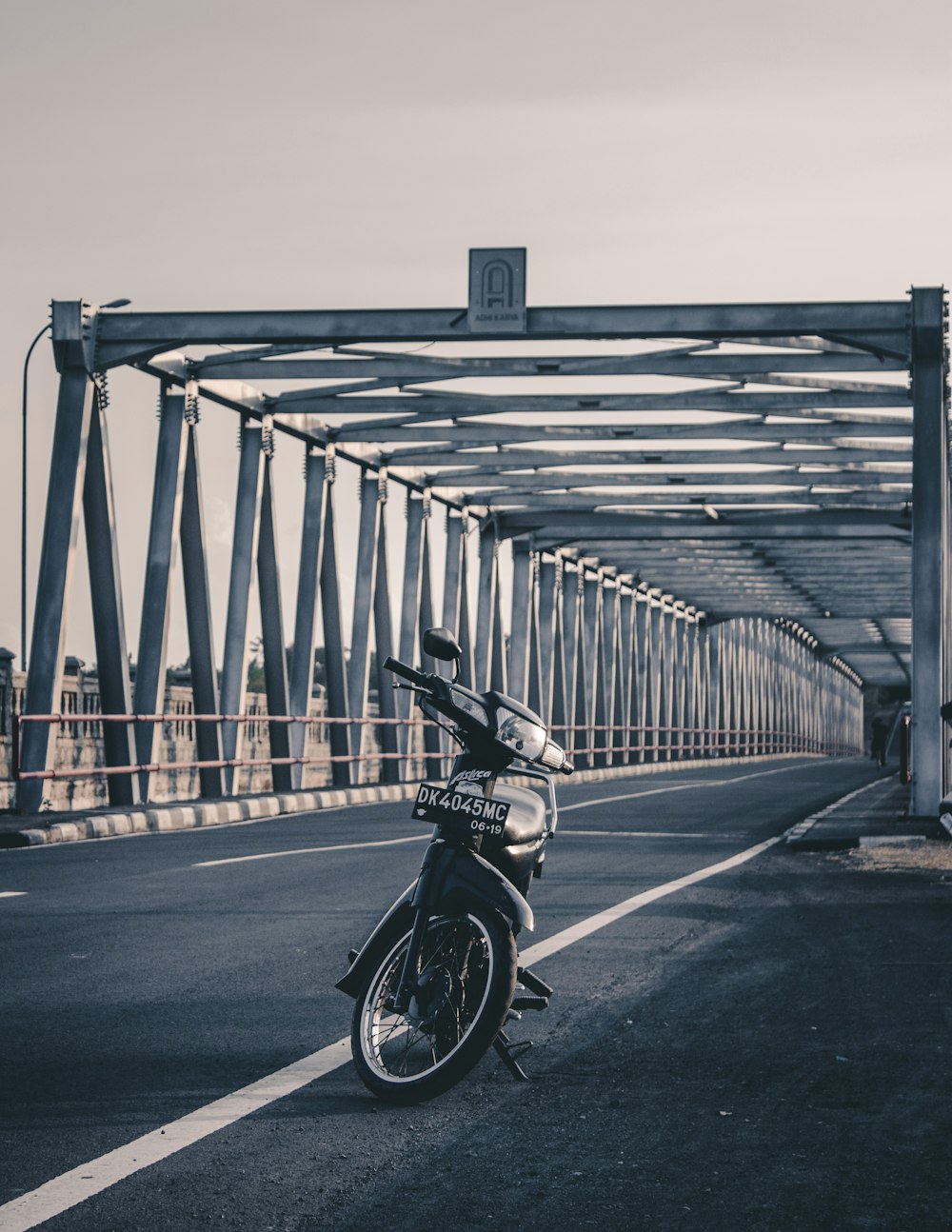 black motorcycle parked on bridge during daytime