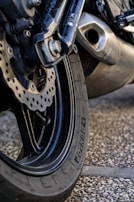 A close-up of a motorcycle's wheel kicking up dirt on a rugged path.