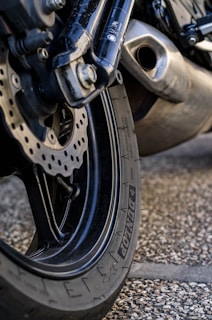 A close-up of a motorcycle's wheel kicking up dirt on a rugged path.