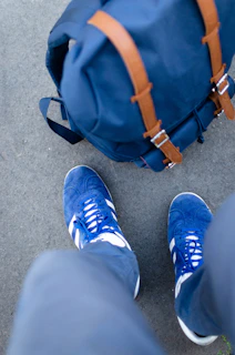 Baby blue sneakers arranged neatly next to a matching blue backpack