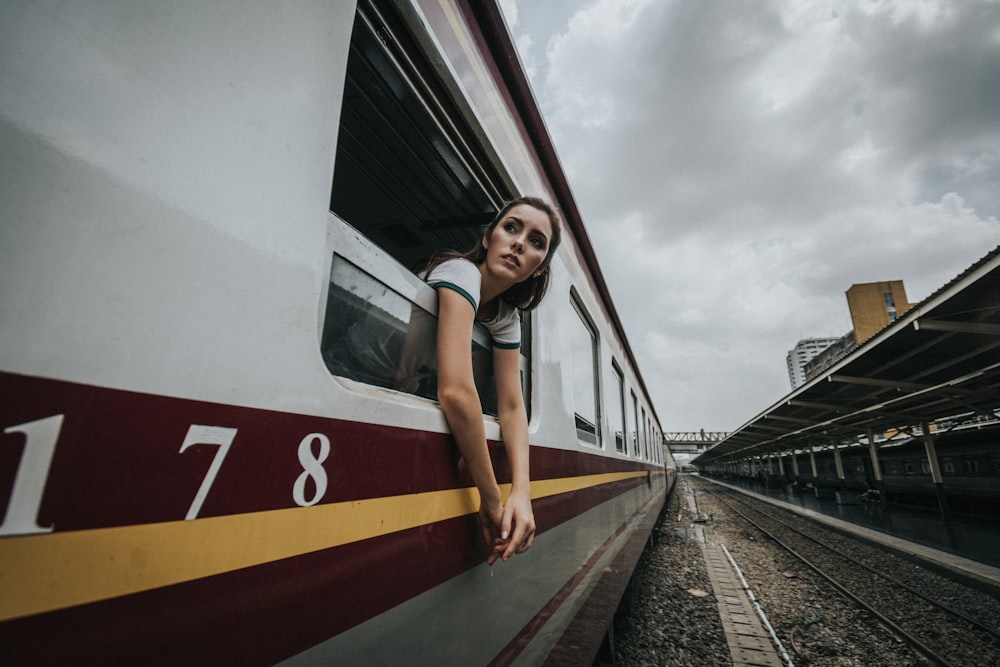 Testa e mani della donna all'esterno del treno sotto il cielo nuvoloso durante il giorno