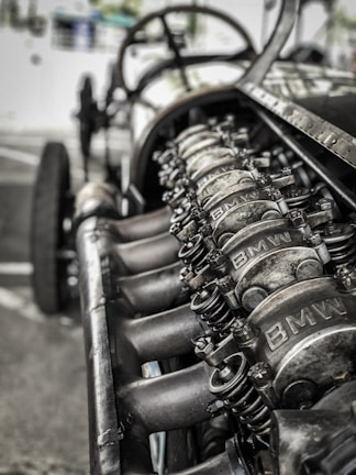 A close-up view of an engine with visible metal components, showcasing intricate mechanical details. The image depicts a raw, industrial look with parts marked with the logo 'BMW'.