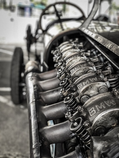 Close-up of a polished vintage BMW engine part resting on a wooden workbench.