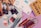 A variety of art supplies are spread out, including tubes of paint, jars of medium, colored pencils, a sketchbook, and sheets of paper. There are several artist paint brushes alongside pencils of different colors arranged neatly, with some paint tubes and medium bottles placed nearby.
