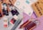 A variety of art supplies are spread out, including tubes of paint, jars of medium, colored pencils, a sketchbook, and sheets of paper. There are several artist paint brushes alongside pencils of different colors arranged neatly, with some paint tubes and medium bottles placed nearby.