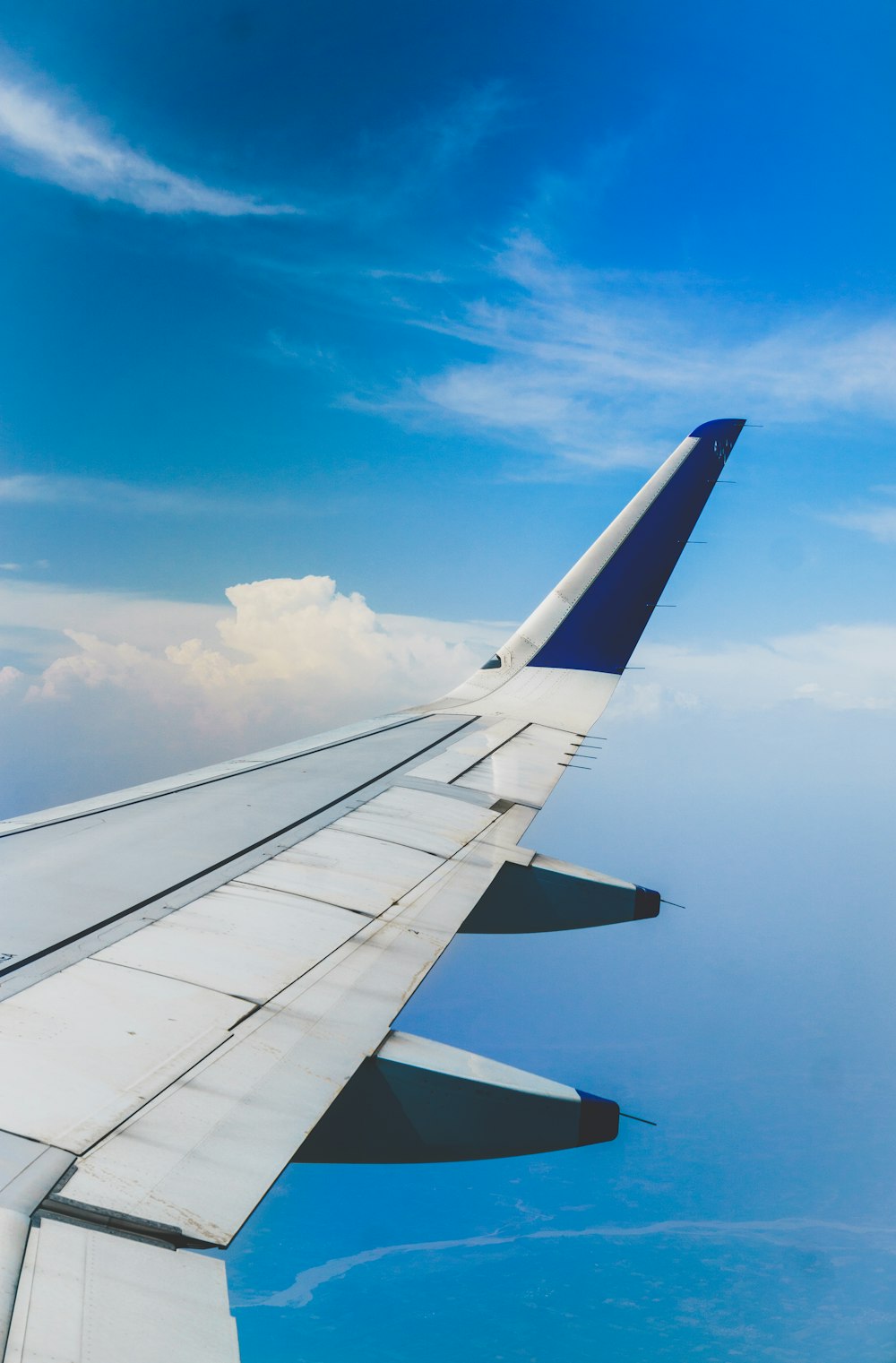 Weißes und blaues Flugzeug fliegt bei bewölktem Wetter