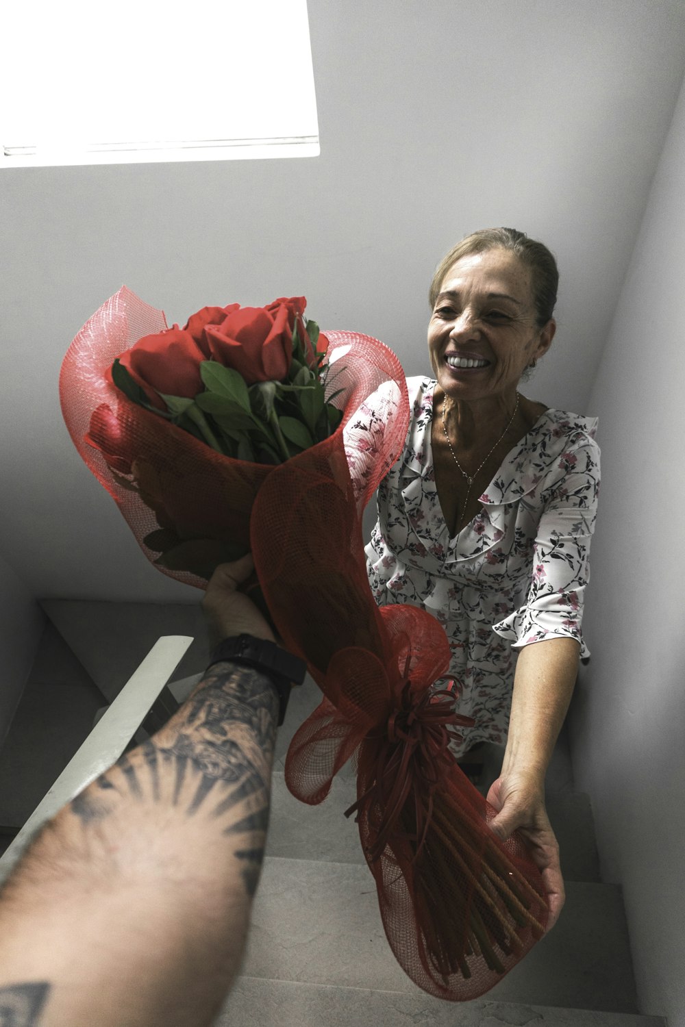 femme souriante recevant un bouquet de roses rouges