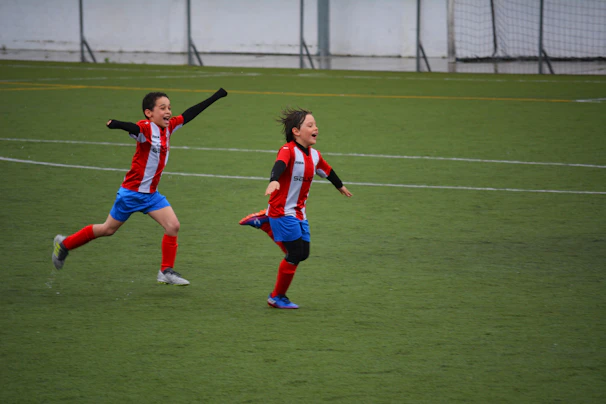 Children celebrating joyfully after scoring a goal during a youth league game.