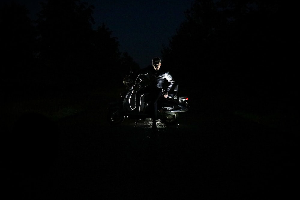 Un homme assis sur une moto dans le noir