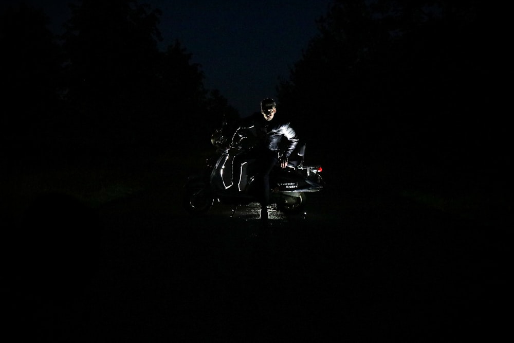a man sitting on a motorcycle in the dark