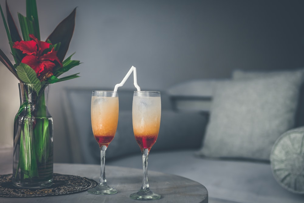 two clear flute glasses beside clear glass vase