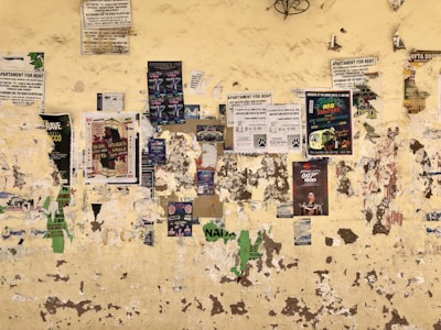 A street wall plastered with various sex ad flyers in different fonts and colors.