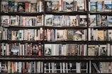 A wall full of bookshelves packed with an assortment of books, primarily travel guides and historical texts. The shelves are filled from end to end, showcasing a diverse collection of titles and colorful spines. The books are neatly arranged, creating a visually appealing and inviting display for browsing readers.