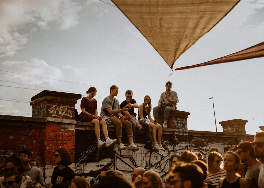 five person sat on brick wall