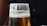 A close-up of a frothy craft beer poured into a clear glass on a wooden bar counter.