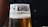 A close-up of a frothy craft beer poured into a clear glass on a wooden bar counter.