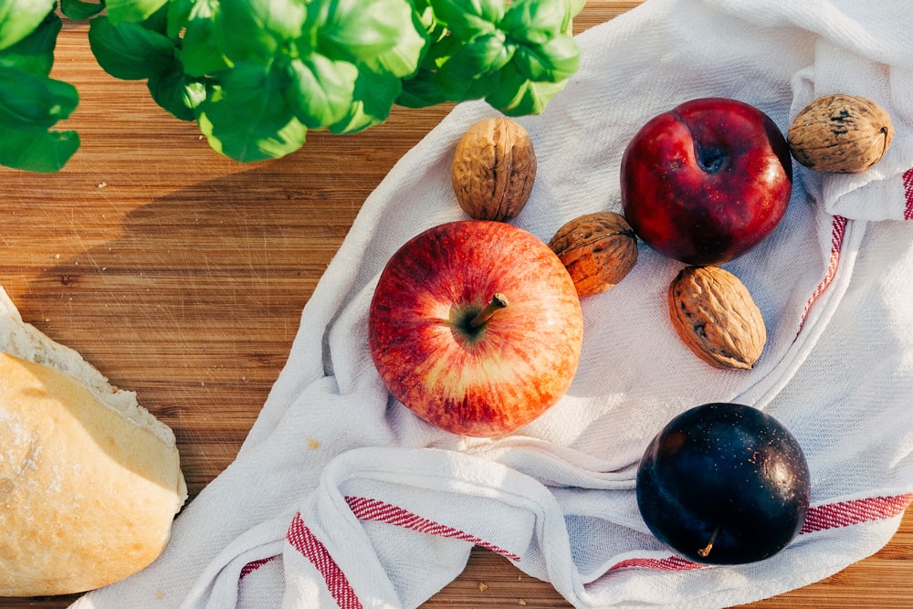 two apples and walnuts on white towel