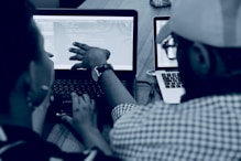 woman using laptop computer beside person wearing hat