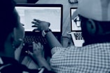 woman using laptop computer beside person wearing hat