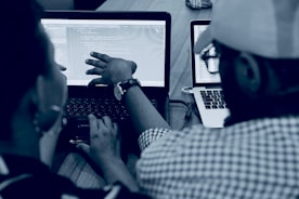 woman using laptop computer beside person wearing hat