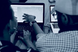 woman using laptop computer beside person wearing hat