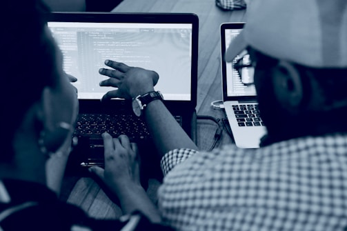 woman using laptop computer beside person wearing hat