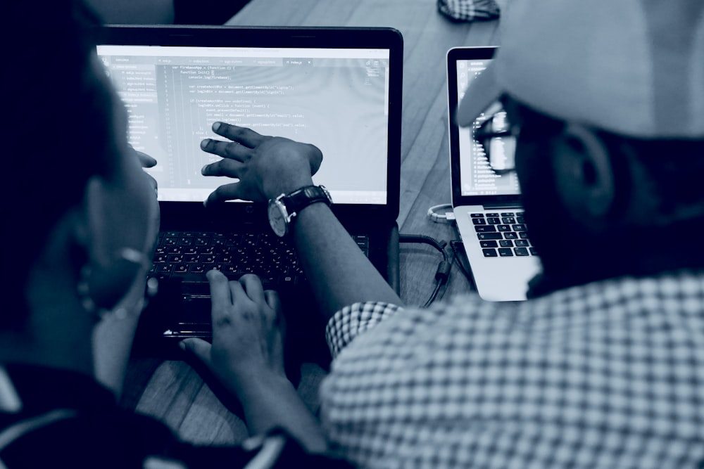 woman using laptop computer beside person wearing hat