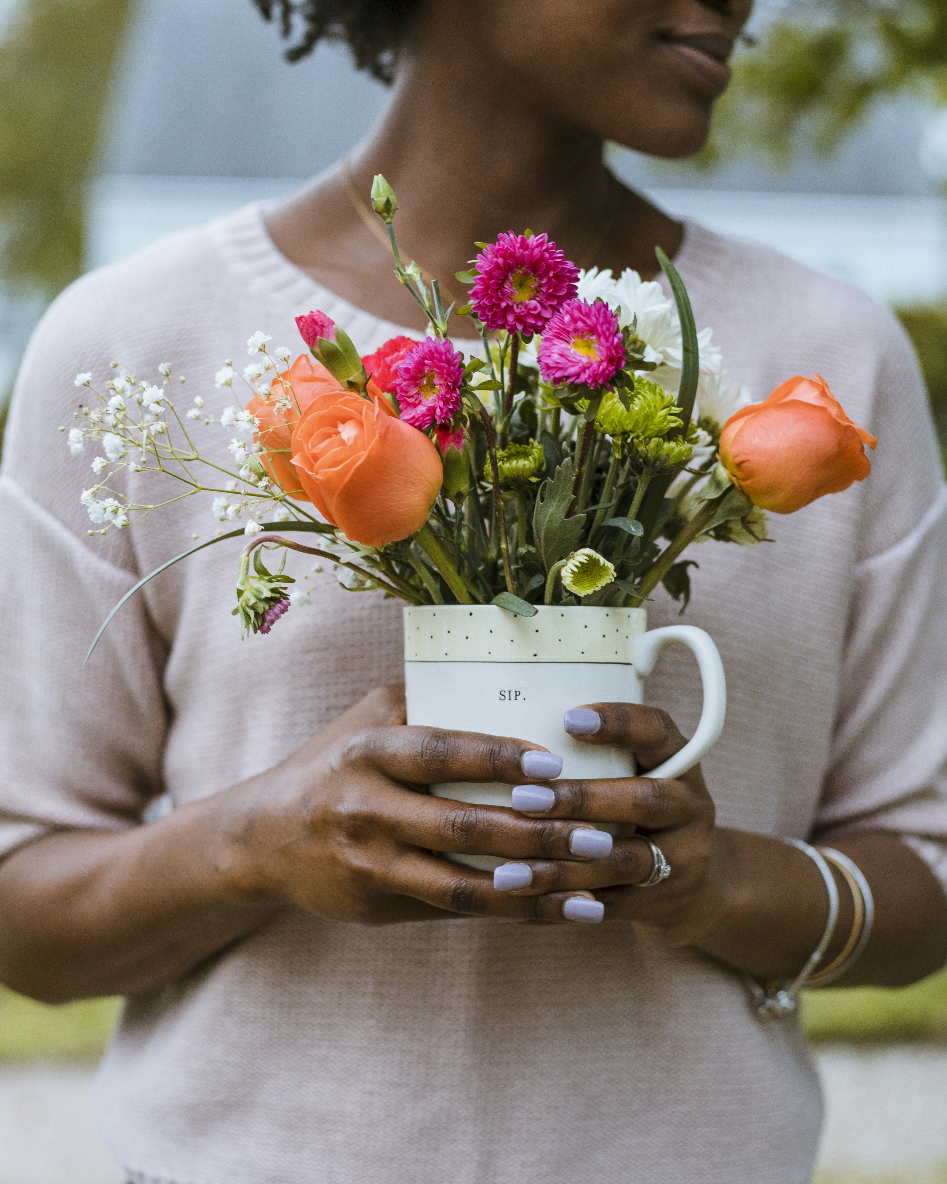 person holding pot of orange pink and white petaled flowerse