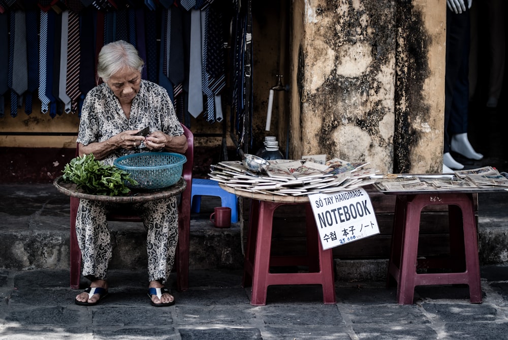 woman sitting on chair slicing vegetables