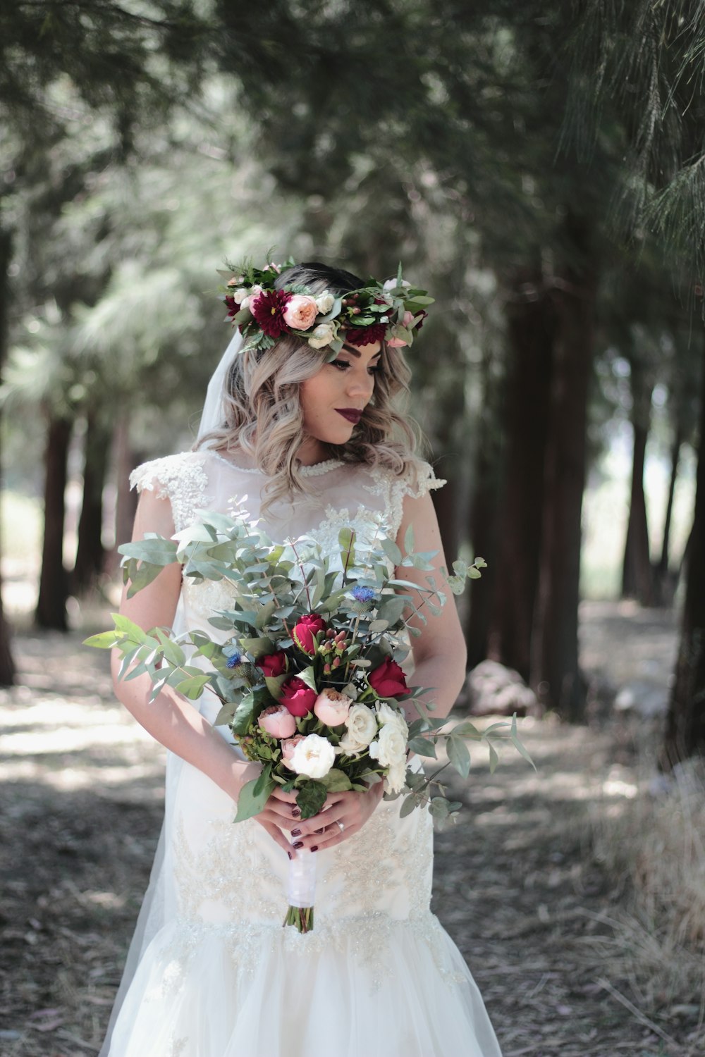 Mujer con vestido de novia blanco sosteniendo ramo de flores
