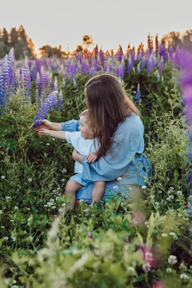 woman sitting with baby on her lap surrounded with purples flower