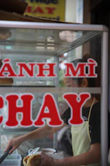 A friendly staff member handing a freshly packed Thai sandwich to a smiling customer at the counter.
