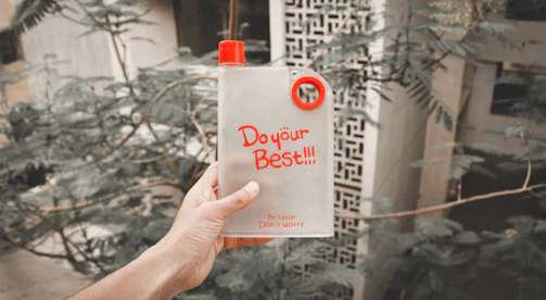 Close-up of hands holding a water bottle and a workout plan.