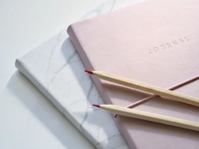 red and purple coloring pencils on pink journal