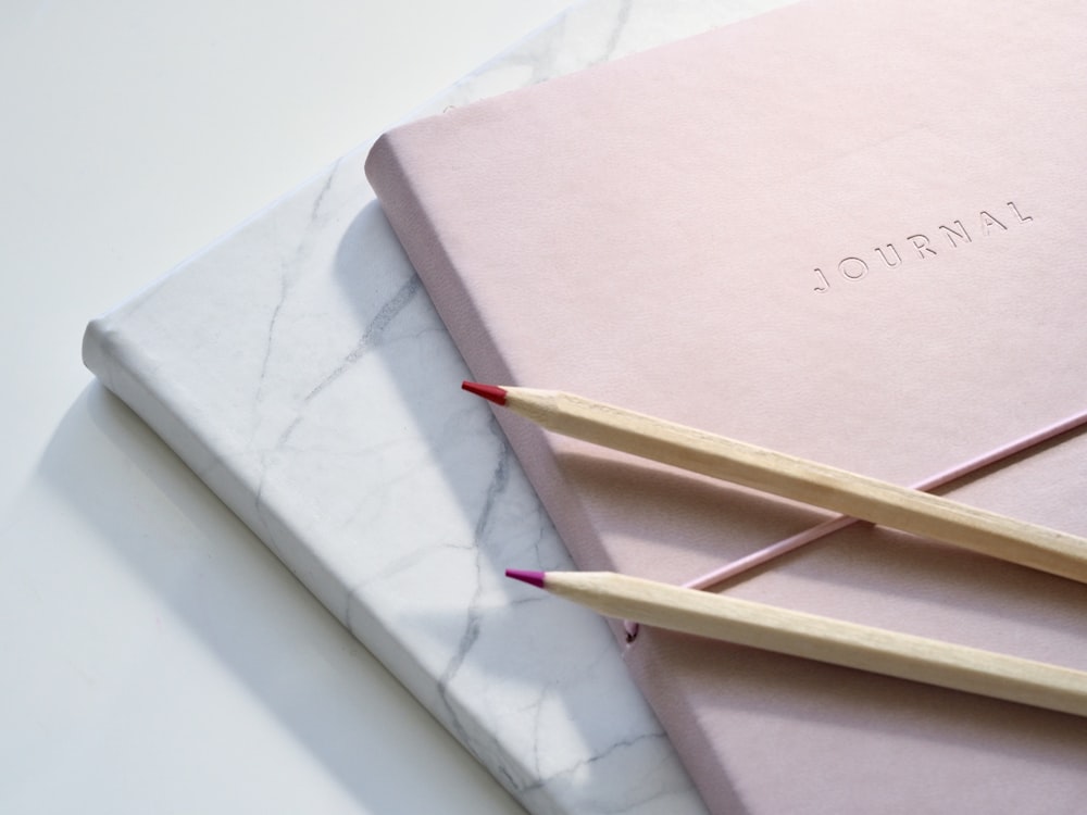 rote und lila Buntstifte auf rosa Notizbuch