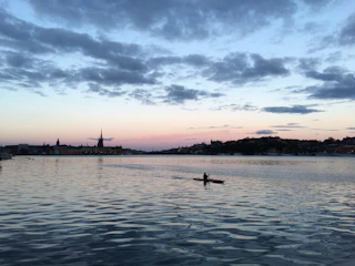 Kayaker paddling through a serene desert oasis surrounded by golden sand dunes at sunset.