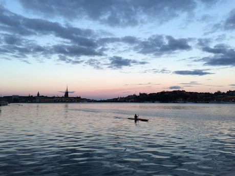 Kayaker paddling through a serene desert oasis surrounded by golden sand dunes at sunset.