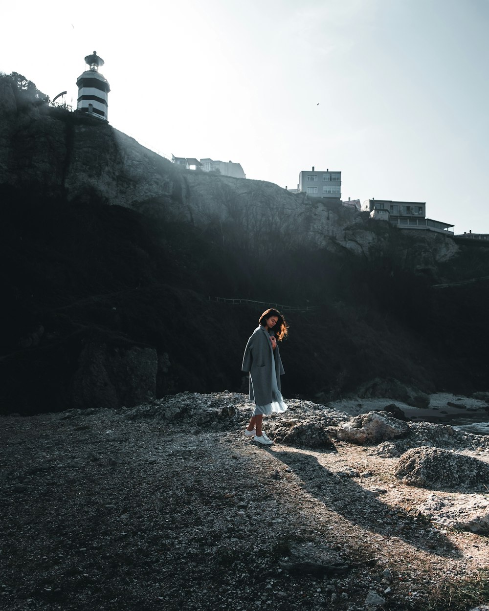 woman with robe at her back walking on stones