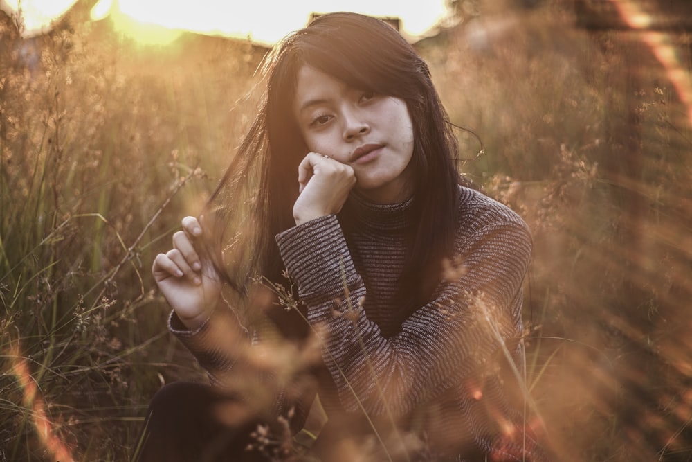 woman sitting surrounded by leaves during daytime