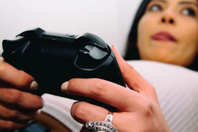 Close-up of hands holding a game controller with a fishing game on the TV in the background.