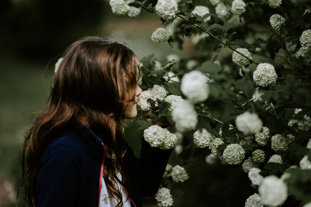 Mujer sosteniendo flores blancas mientras mira de lado