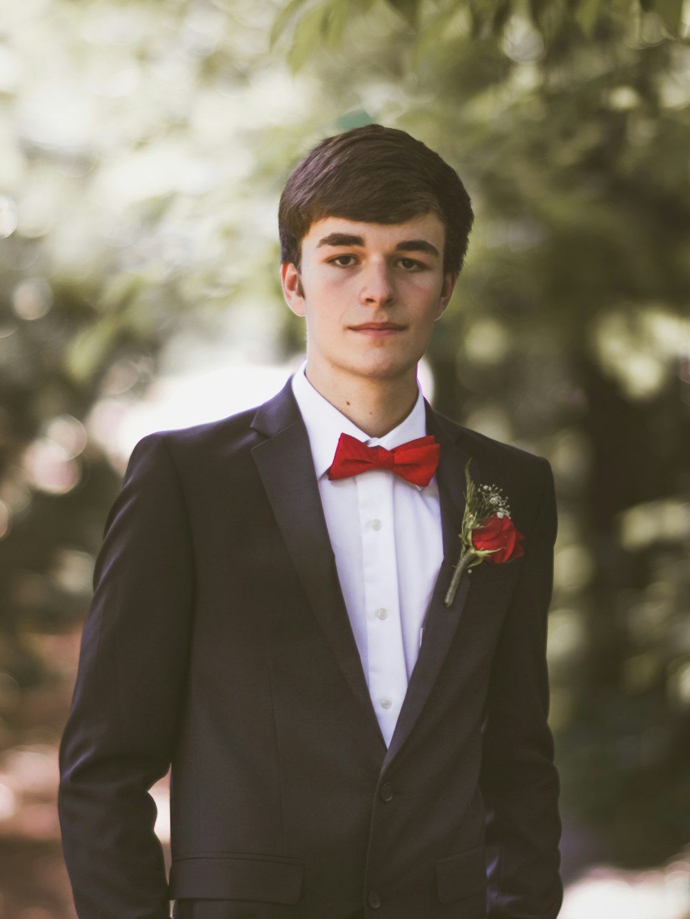 shallow focus photography of man standing under the tree while taking him picture