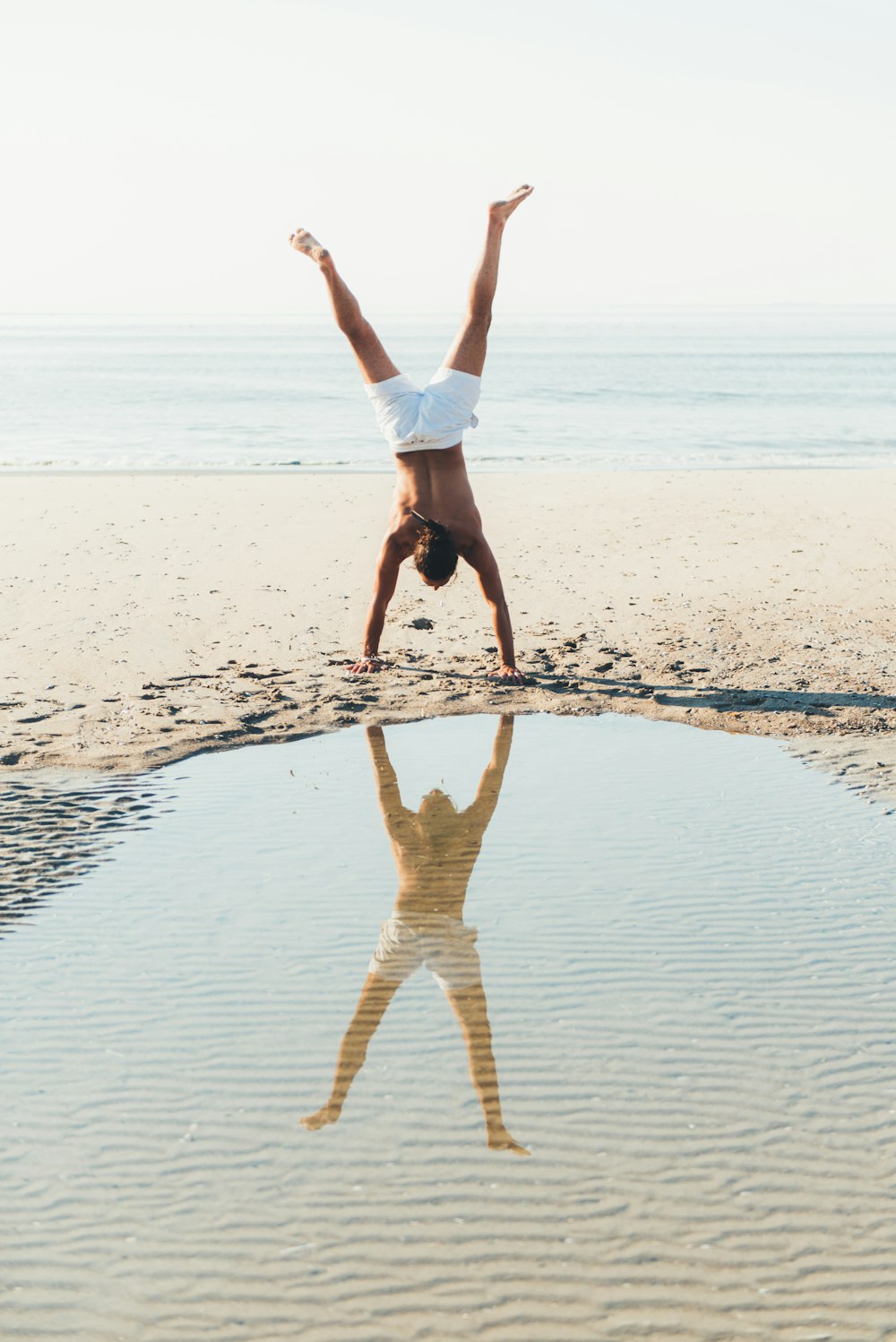 person doing cartwheel on seashore