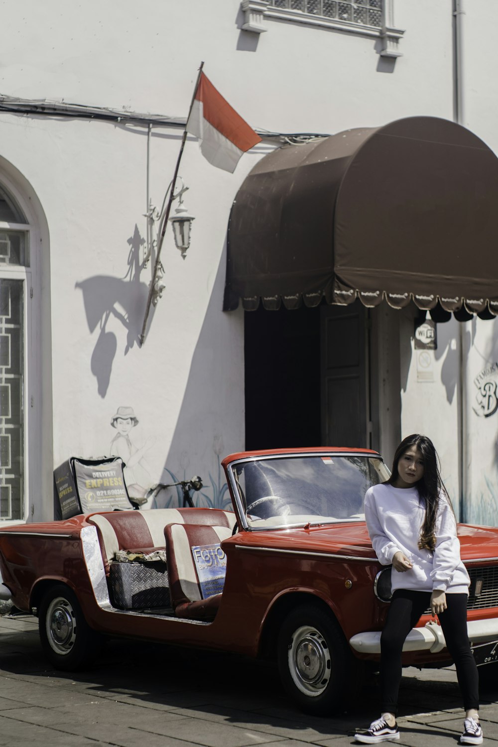 woman leaning on red and white coupe