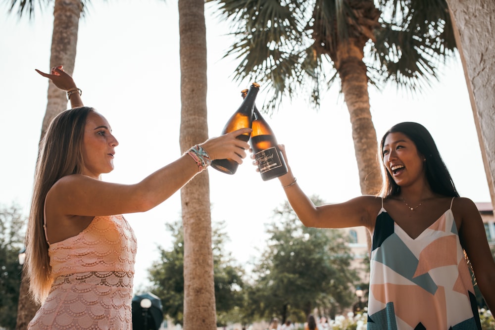 two woman holding beer bottles