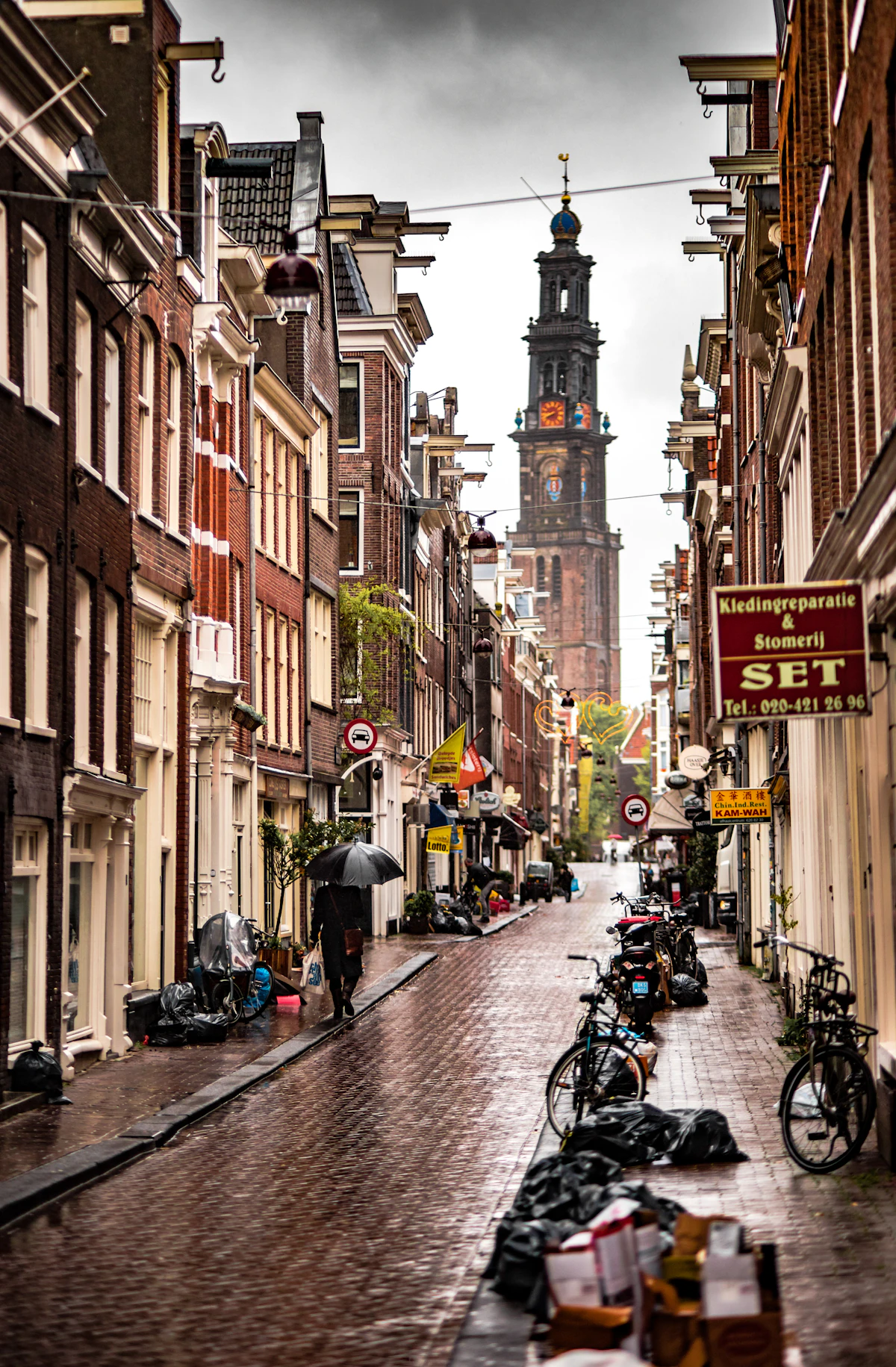 Person with gray umbrella walking on wet Amsterdam street