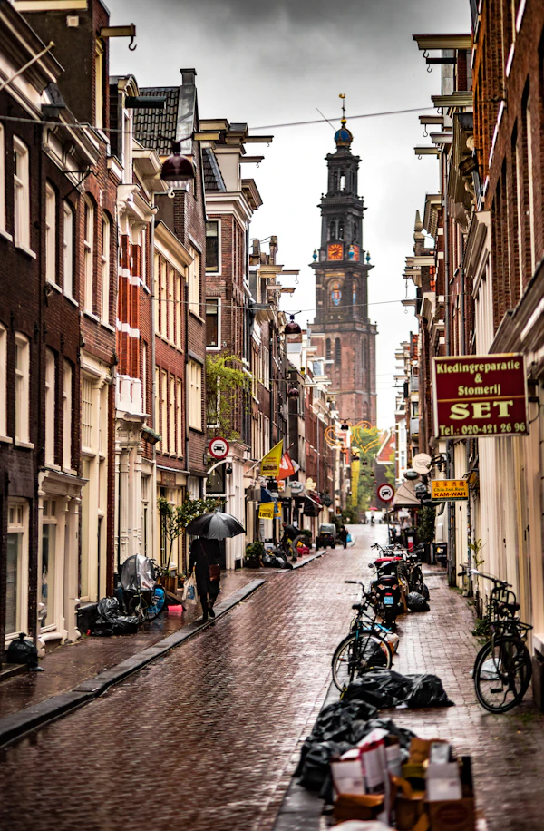 Person with gray umbrella walking on wet Amsterdam street