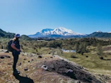 A traveler with a backpack standing on a mountain peak overlooking a vast landscape.
