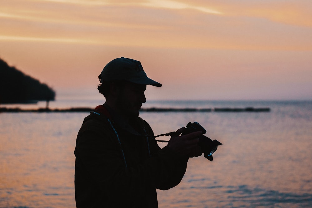 hombre haciendo fotografía con una cámara DSLR cerca de un cuerpo de agua